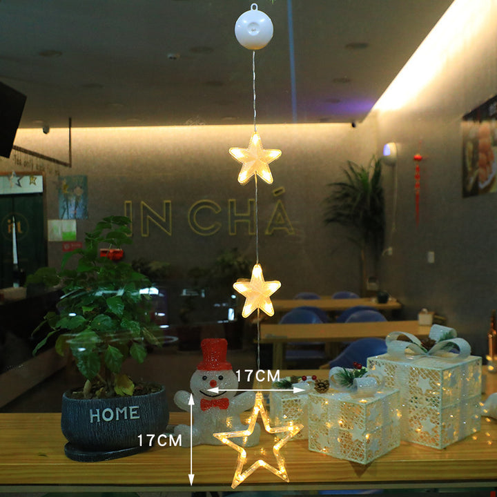 Three warm-white Christmas pendants glowing in window